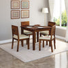 A solid Sheesham wood dining table with four chairs around it, placed on a rug in a room with decorative curtains and a lamp on the side.