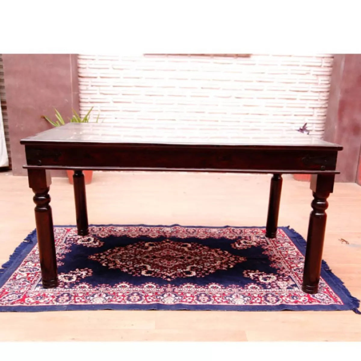 Dark wooden table on a patterned rug with a window in the background