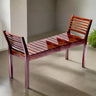 Wooden bench with slatted design on a concrete floor.