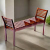 Wooden bench with slatted design on a concrete floor.