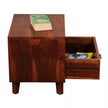 Wooden side table with open drawer containing books on a white background