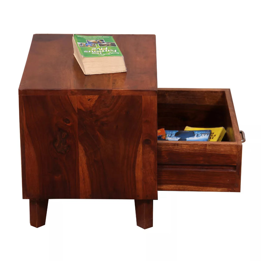 Wooden side table with open drawer containing books on a white background