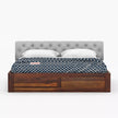 Wooden bed with gray upholstered headboard and white bedding on a white background