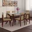 Dining room set with a glass table and wooden chairs on a rug.