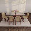 Dining table set with six chairs in a room with wooden floor and white walls.