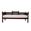 Wooden daybed with intricate carvings and a white cushion on a white background