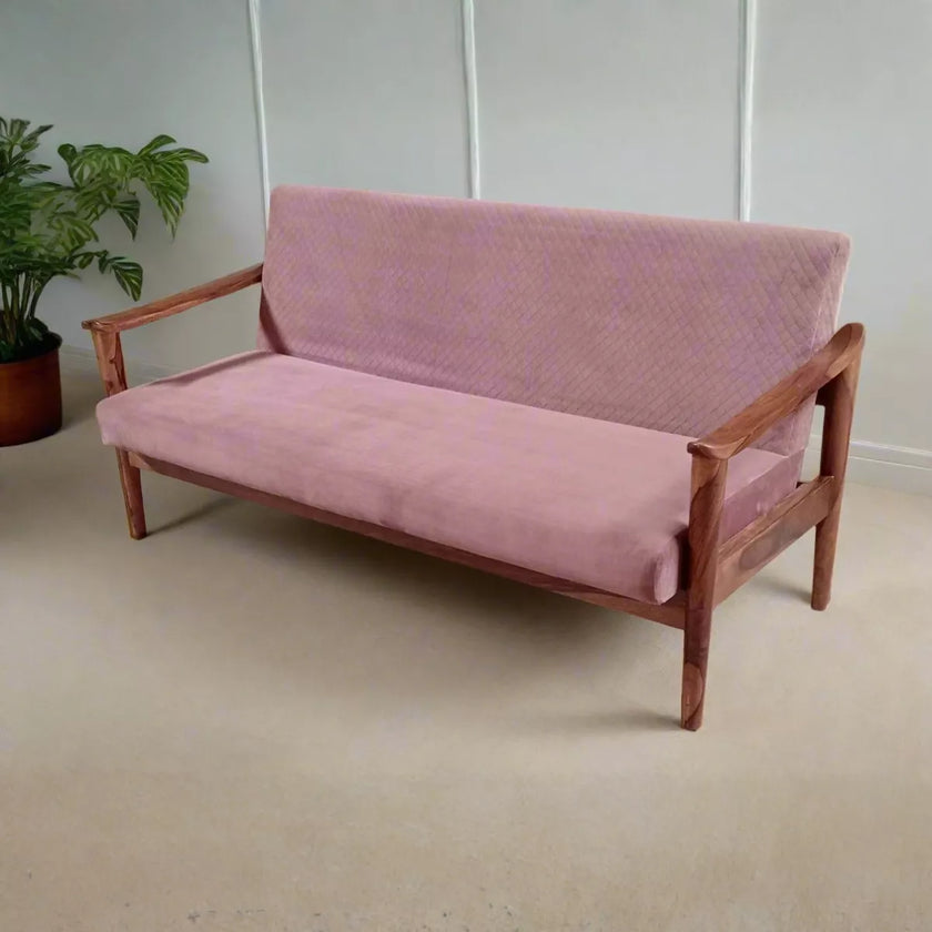 Pink sofa with wooden frame on a beige floor, plant in the background