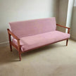 Pink sofa with wooden frame in a room with beige carpet and white walls