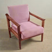 Pink sofa chair with wooden frame on a beige floor and light gray wall background
