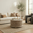 Aarav carved round coffee table in white distressed finish in a living room