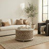 Aarav carved round coffee table in white distressed finish in a living room