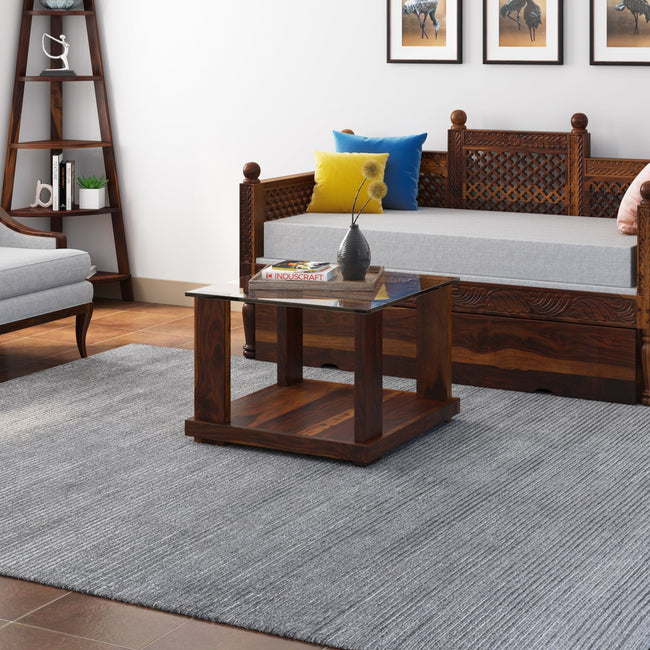 Aeron square glass top sheesham coffee table beside a wooden sofa