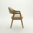 Side view of Brendon upholstered dining chair with solid wood frame and cushioned beige fabric seat.