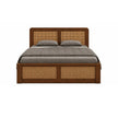 A wooden platform bed with a dark brown finish and woven cane panels on the headboard and footboard, dressed in a gray quilt and two gray pillows, shown against a plain white background.