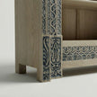 Closeup view of Meher rustic teak wood hand-carved display cabinet emphasizing light wood shelves and carved pedestal base